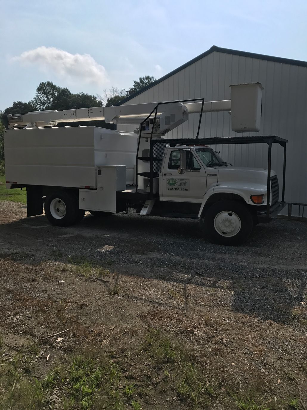 A white bucket truck is parked in front of a building.