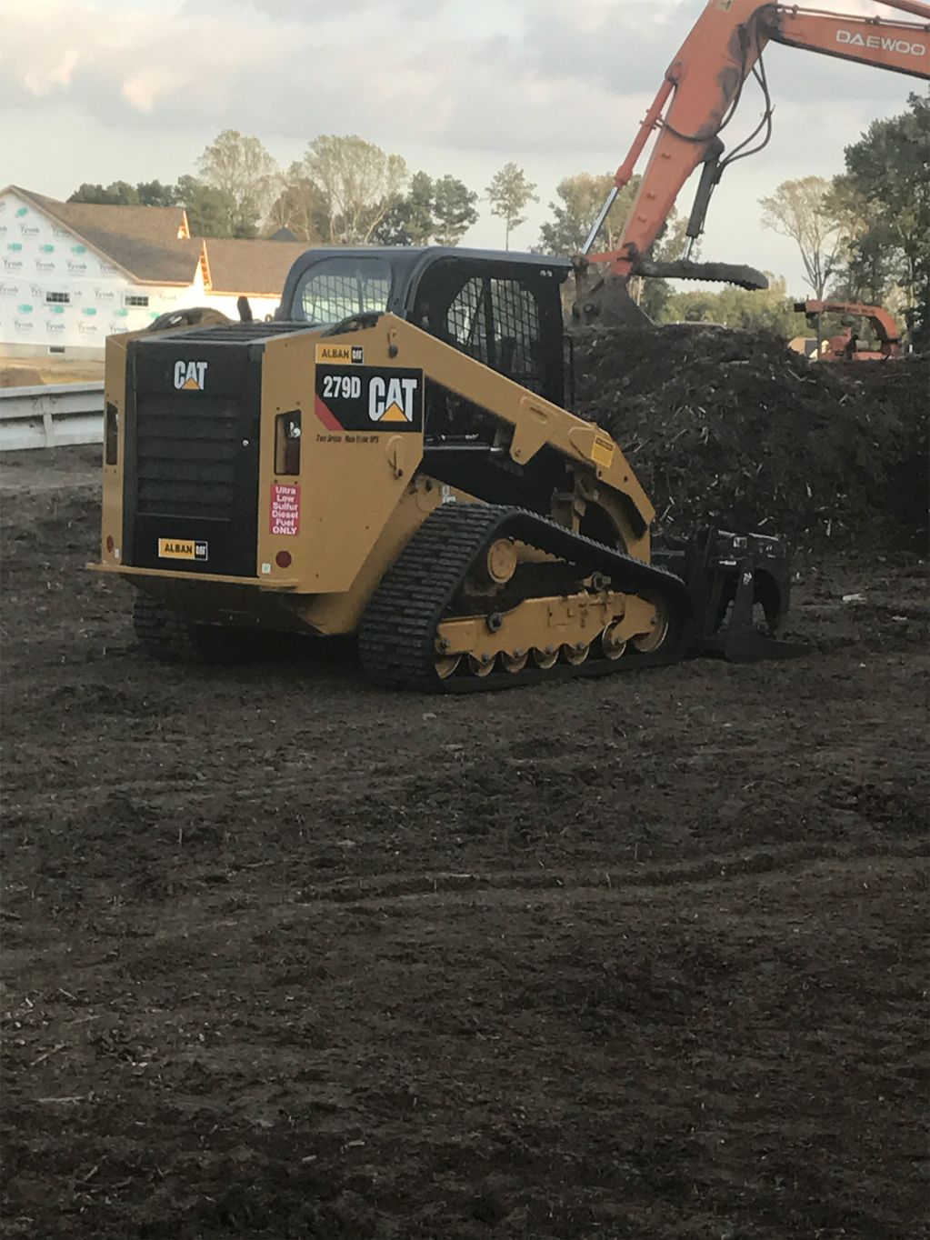 A cat bulldozer is sitting in a dirt field next to a pile of dirt.