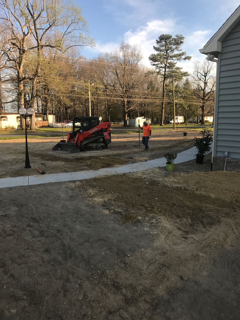 A man is standing next to a bulldozer in a driveway.
