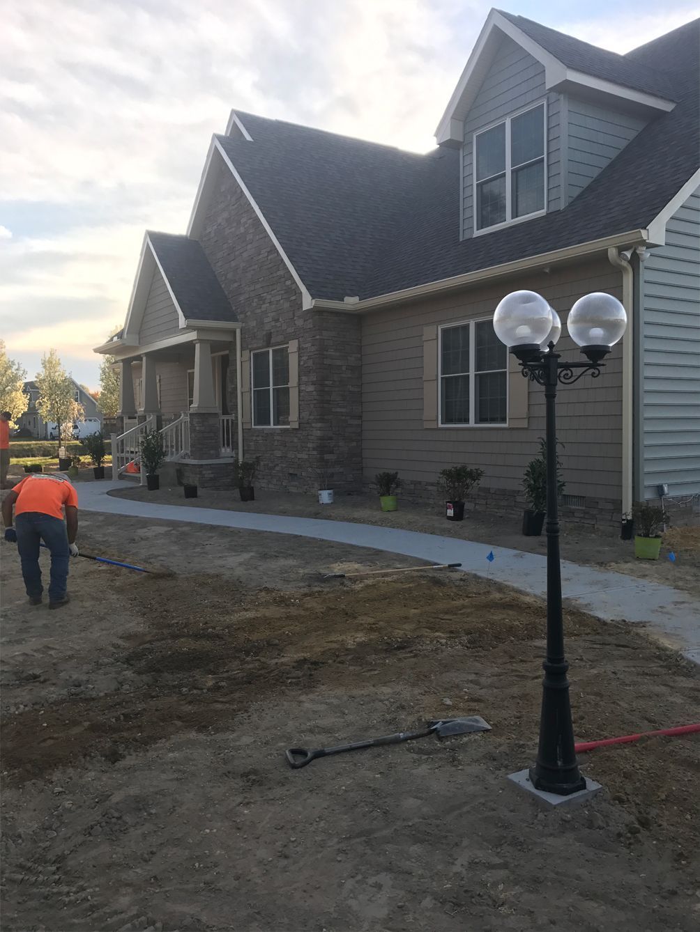 A man is standing in front of a house with a lamp post in front of it.