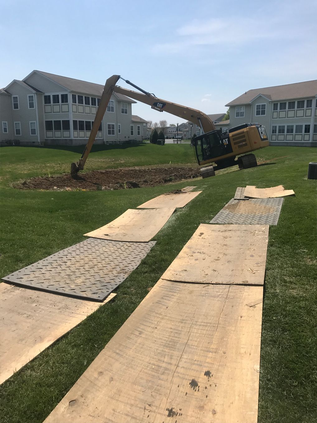 A large excavator is digging a hole in a grassy field.