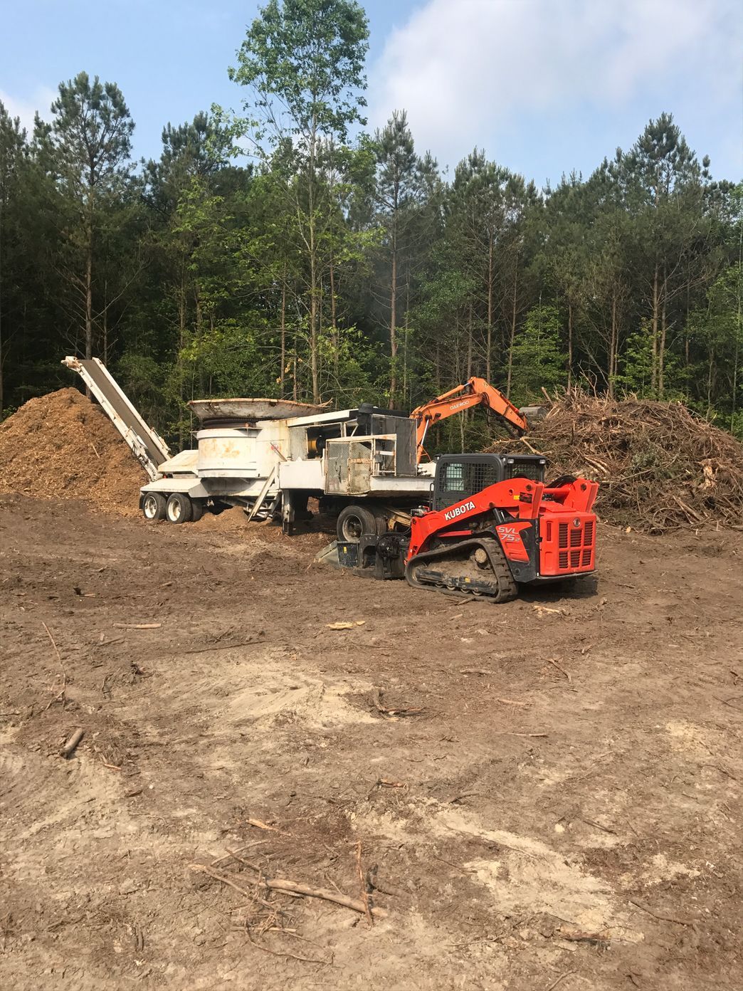 A bulldozer is parked in a dirt field next to a truck.