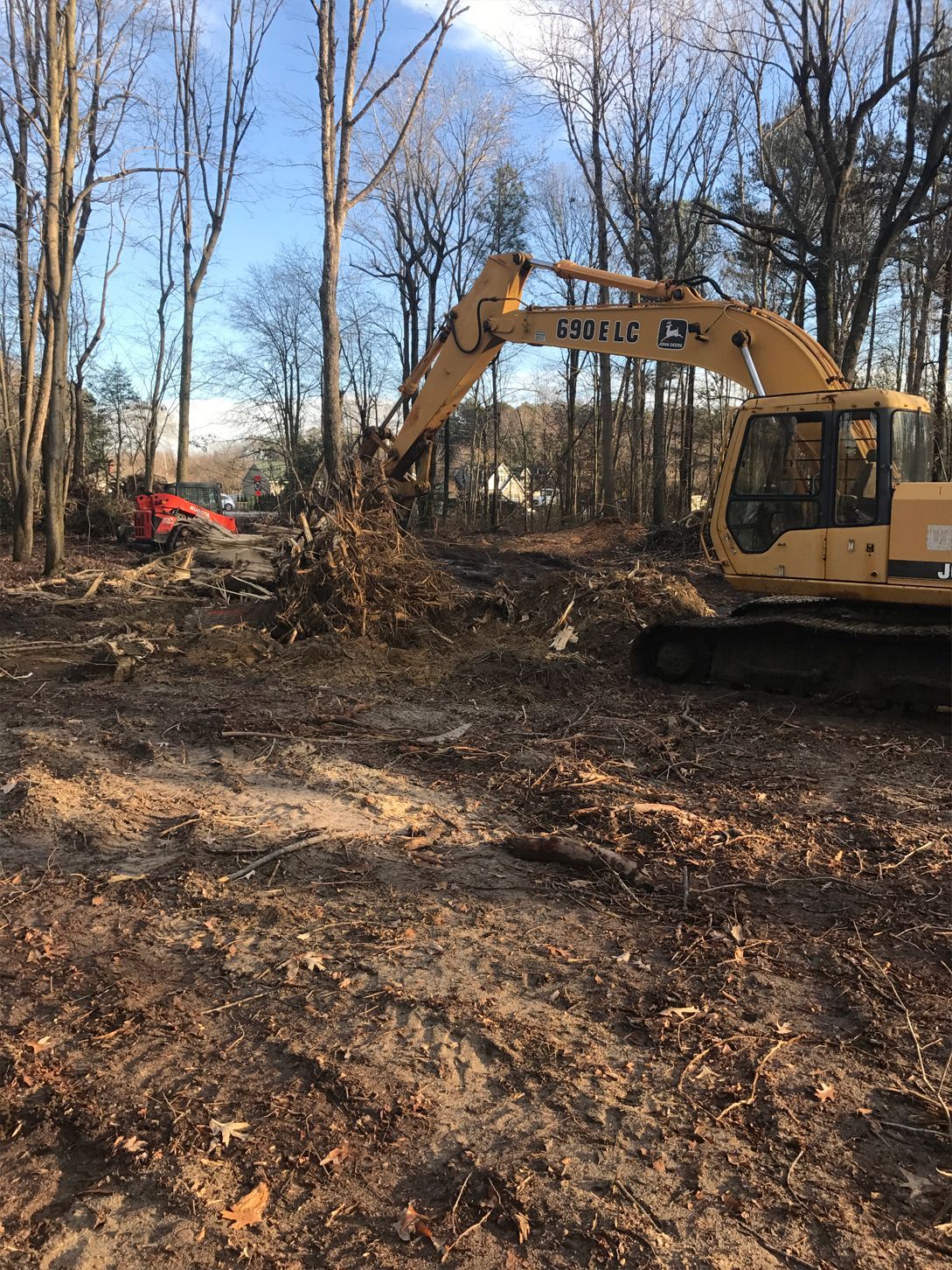 A large yellow excavator is sitting in the middle of a forest.