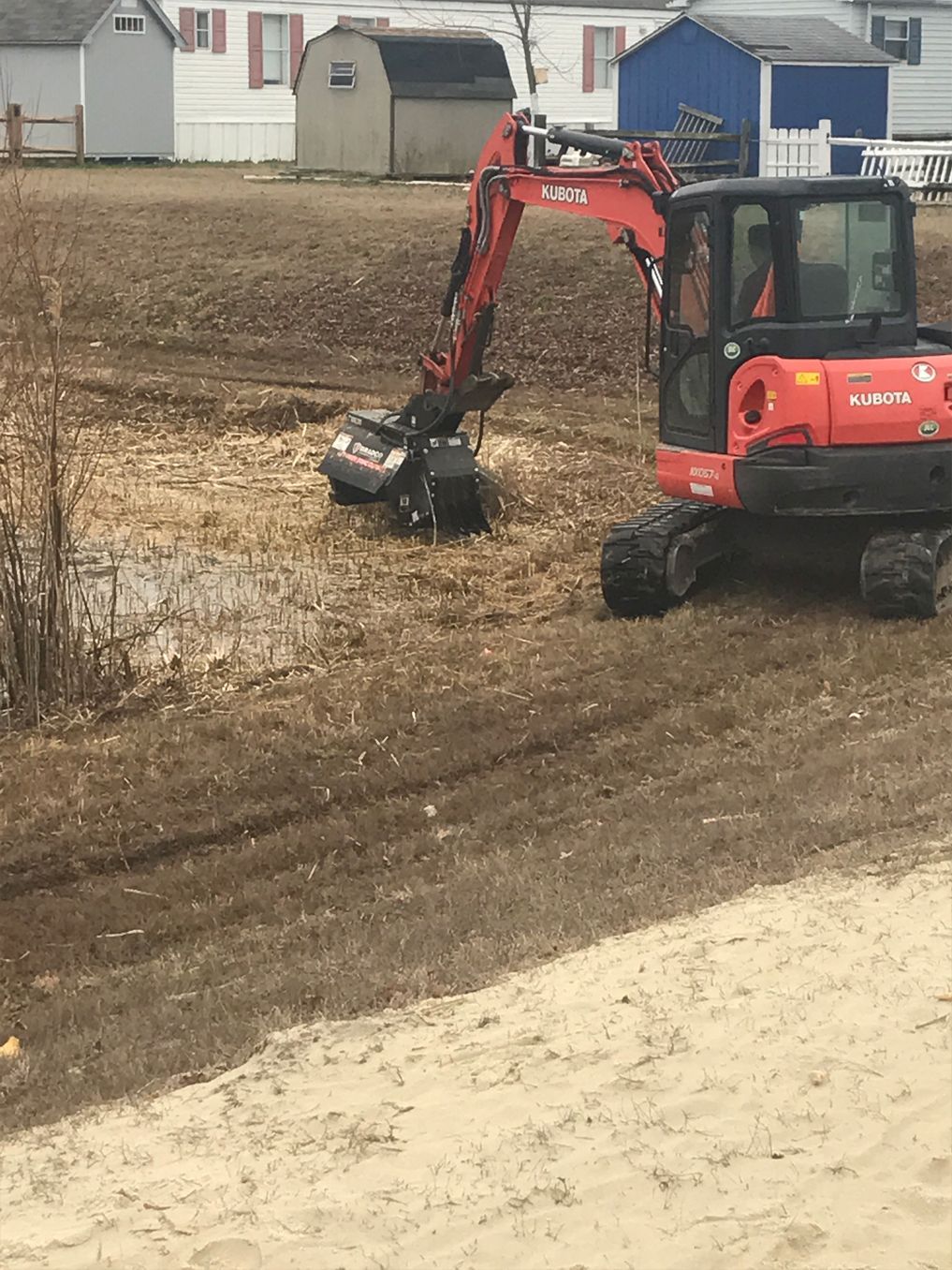 A red and black excavator is driving through a dirt field.