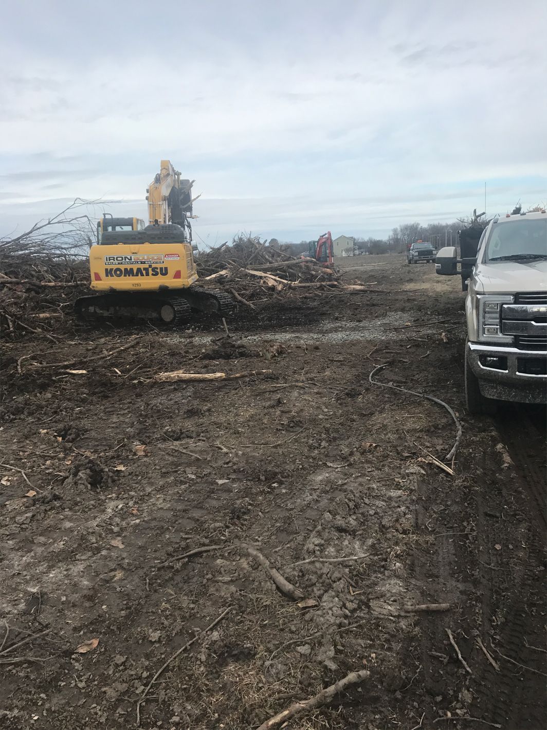 A truck is parked next to a bulldozer in a dirt field.