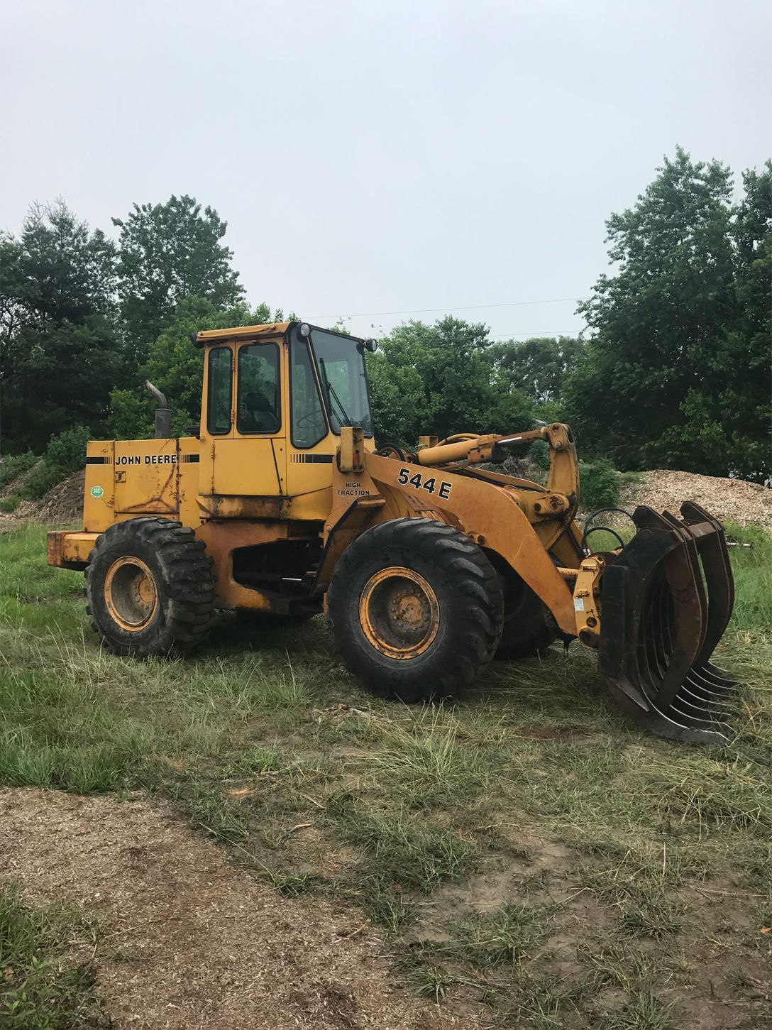 A yellow wheel loader is parked in a grassy field.