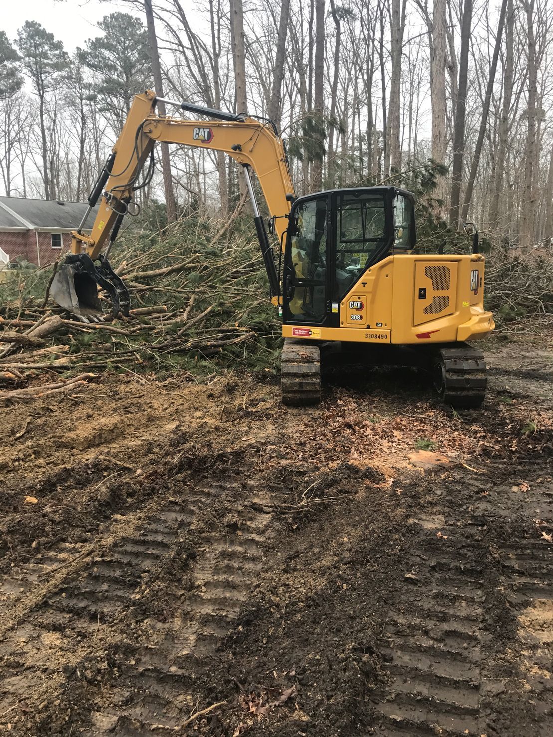 A yellow excavator is sitting in the middle of a dirt field.