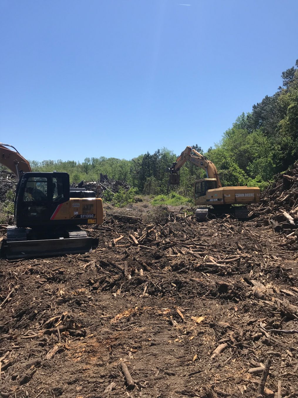Two excavators are working in a pile of dirt.