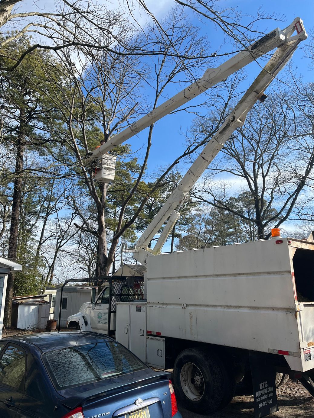 A white truck with a crane on top of it is parked next to a car.