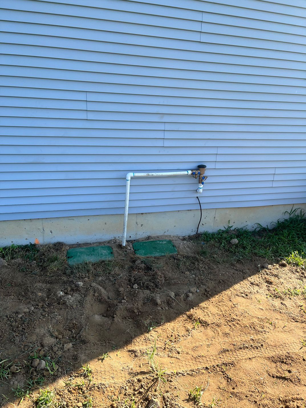 A white house with a hose attached to the side of it.