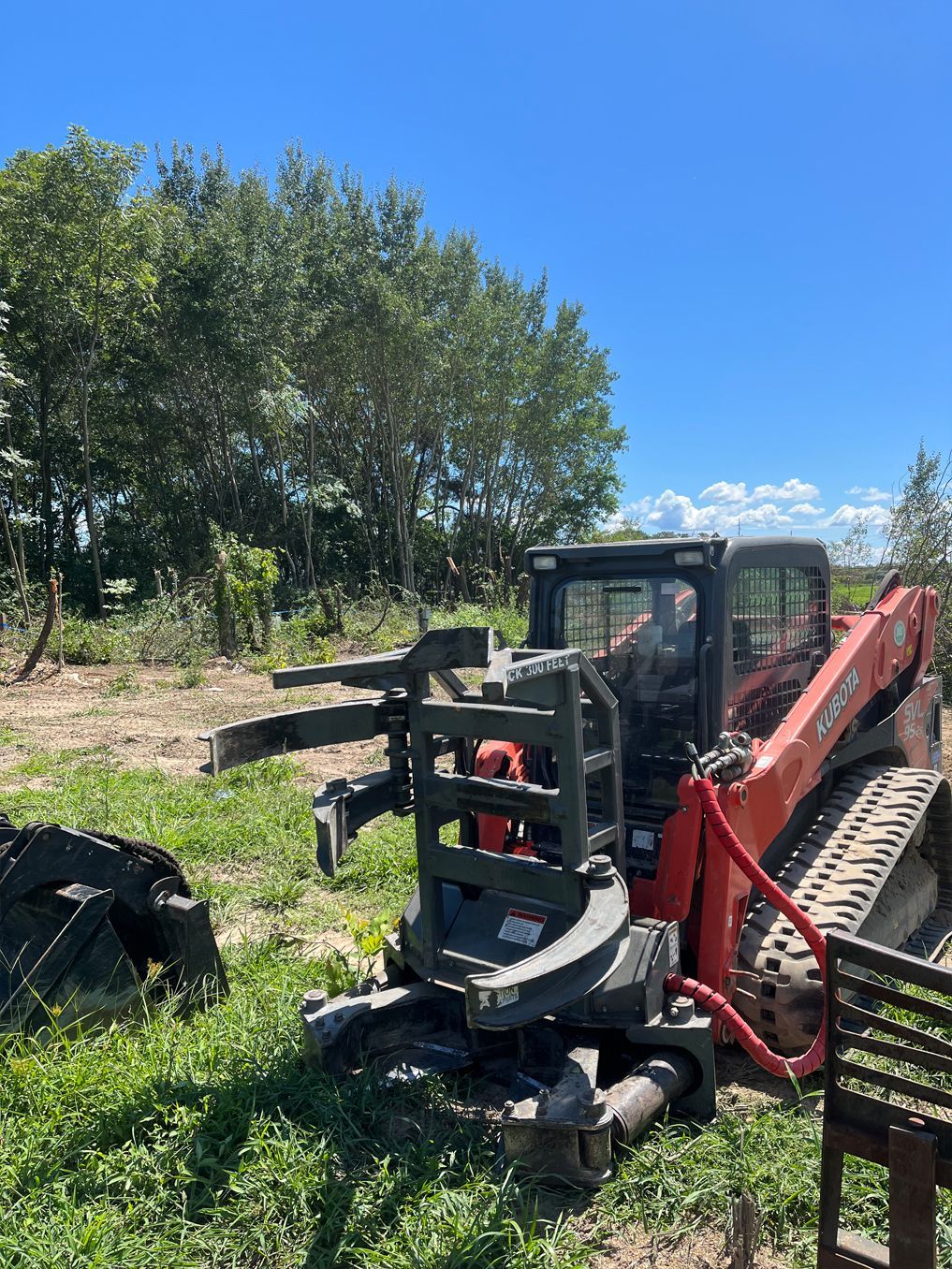 A red and black tractor is parked in a grassy field.