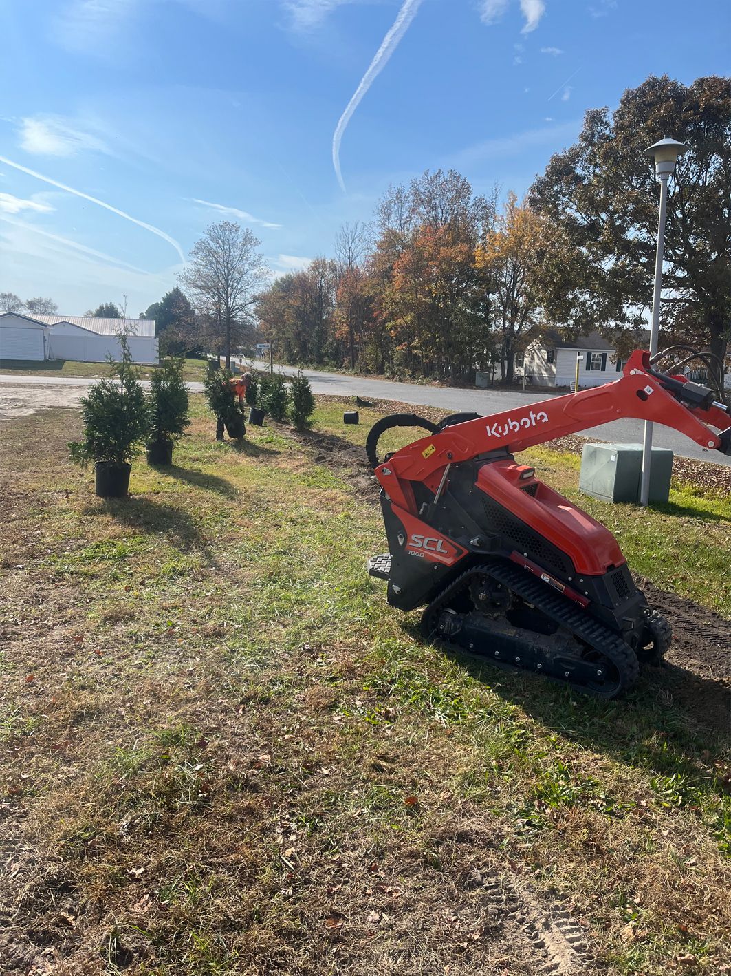 A red tractor is parked in a grassy field next to a road.