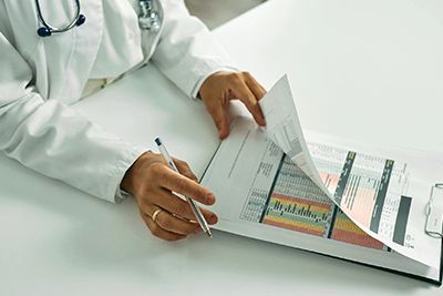 A doctor is sitting at a desk looking at a clipboard.