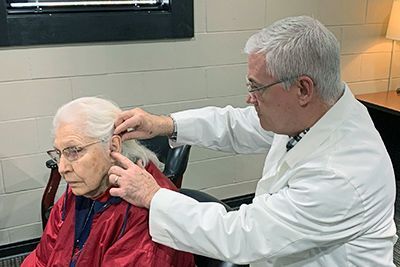 A doctor is examining an elderly woman 's ear.