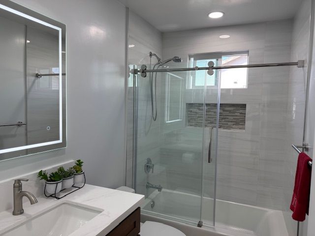 Modern bathroom with glass shower, white walls, vanity, and a red towel.