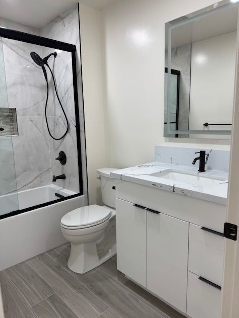 Modern white bathroom with marble-look surfaces, black fixtures, and gray flooring.
