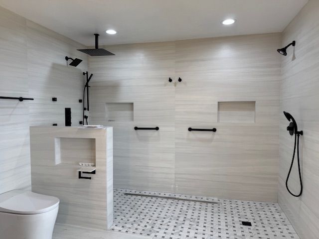 Modern, accessible bathroom with white tiled walls, multiple shower heads, and grab bars.