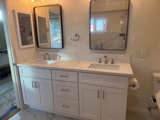 White double bathroom vanity with two rectangular mirrors, sinks, and faucets.