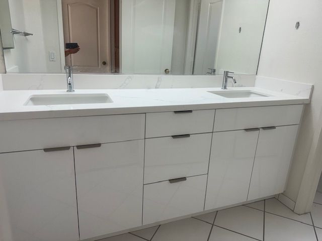 White double vanity with rectangular sinks, chrome faucets, and silver handles, in a bathroom.