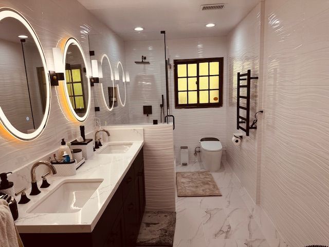 Modern white bathroom with double vanity, oval mirrors, and black fixtures.