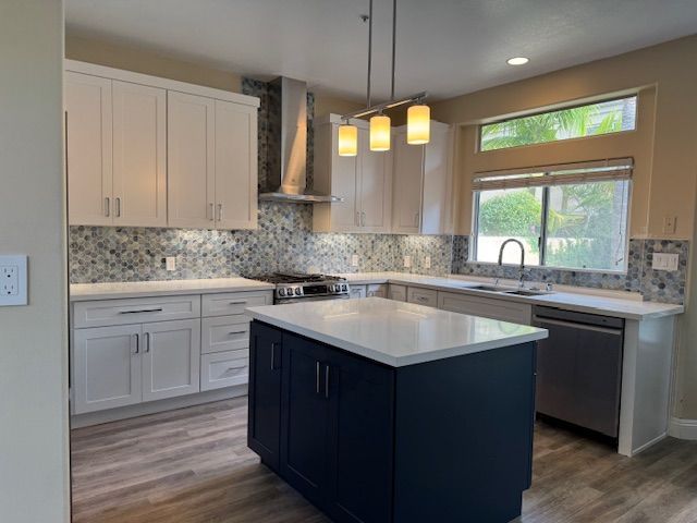 Modern kitchen with white and navy cabinets, island, stainless steel appliances, and patterned backsplash.