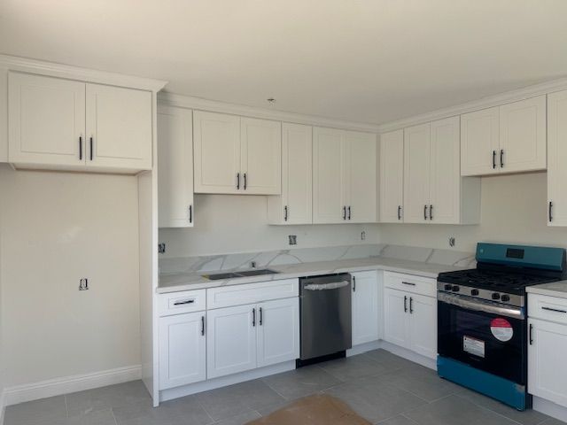 White kitchen with cabinets, stainless steel appliances, and gas stove.