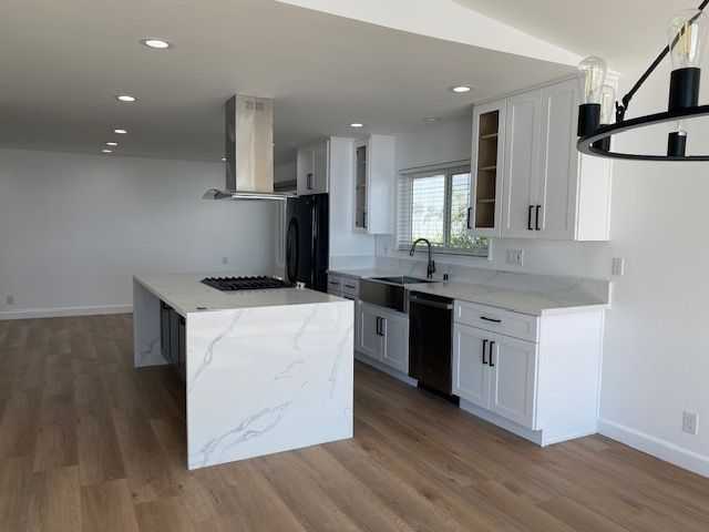 Modern white kitchen with island, stainless steel appliances, and wood flooring.