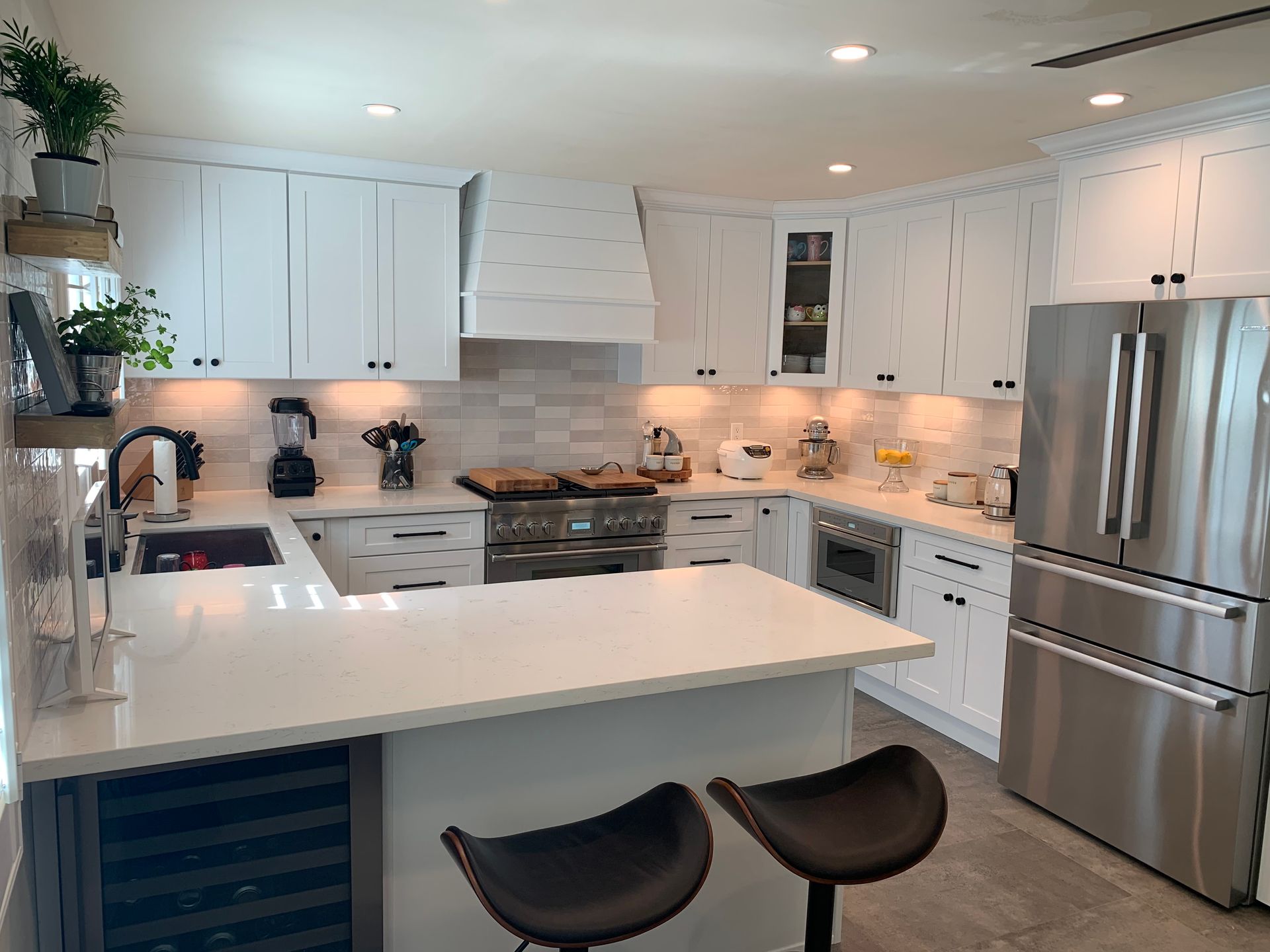 White modern kitchen with stainless steel appliances, countertops, and two barstools.