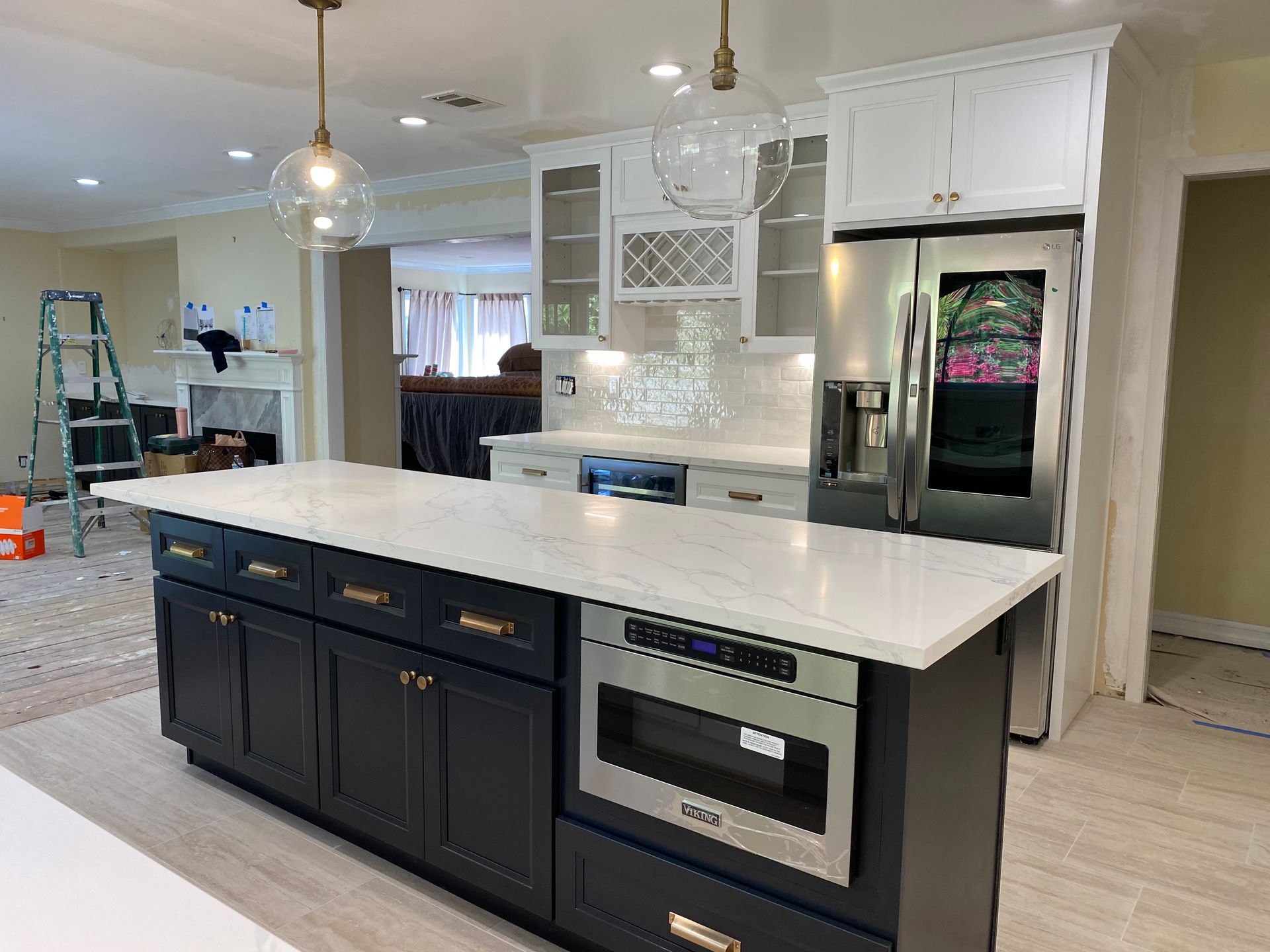 Newly renovated kitchen with dark blue island, white countertops, and stainless steel appliances.