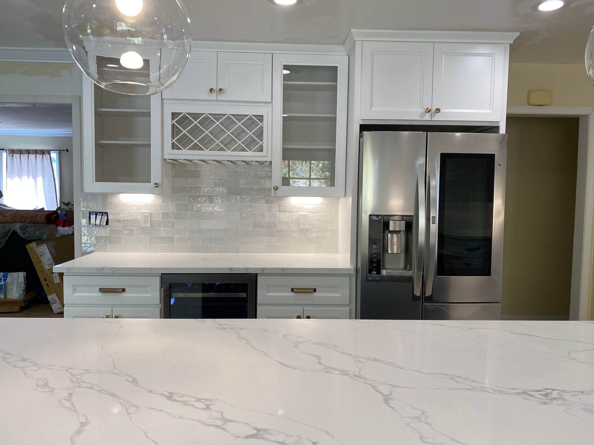 White kitchen with stainless steel appliances, marble countertops, and cabinets.