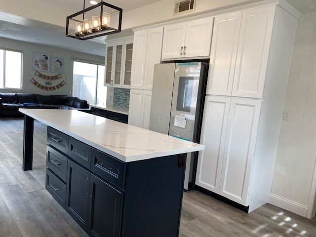 A kitchen with white cabinets and an island with black cabinets