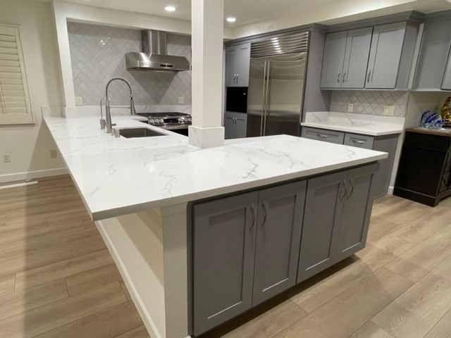A kitchen with gray cabinets and white countertops