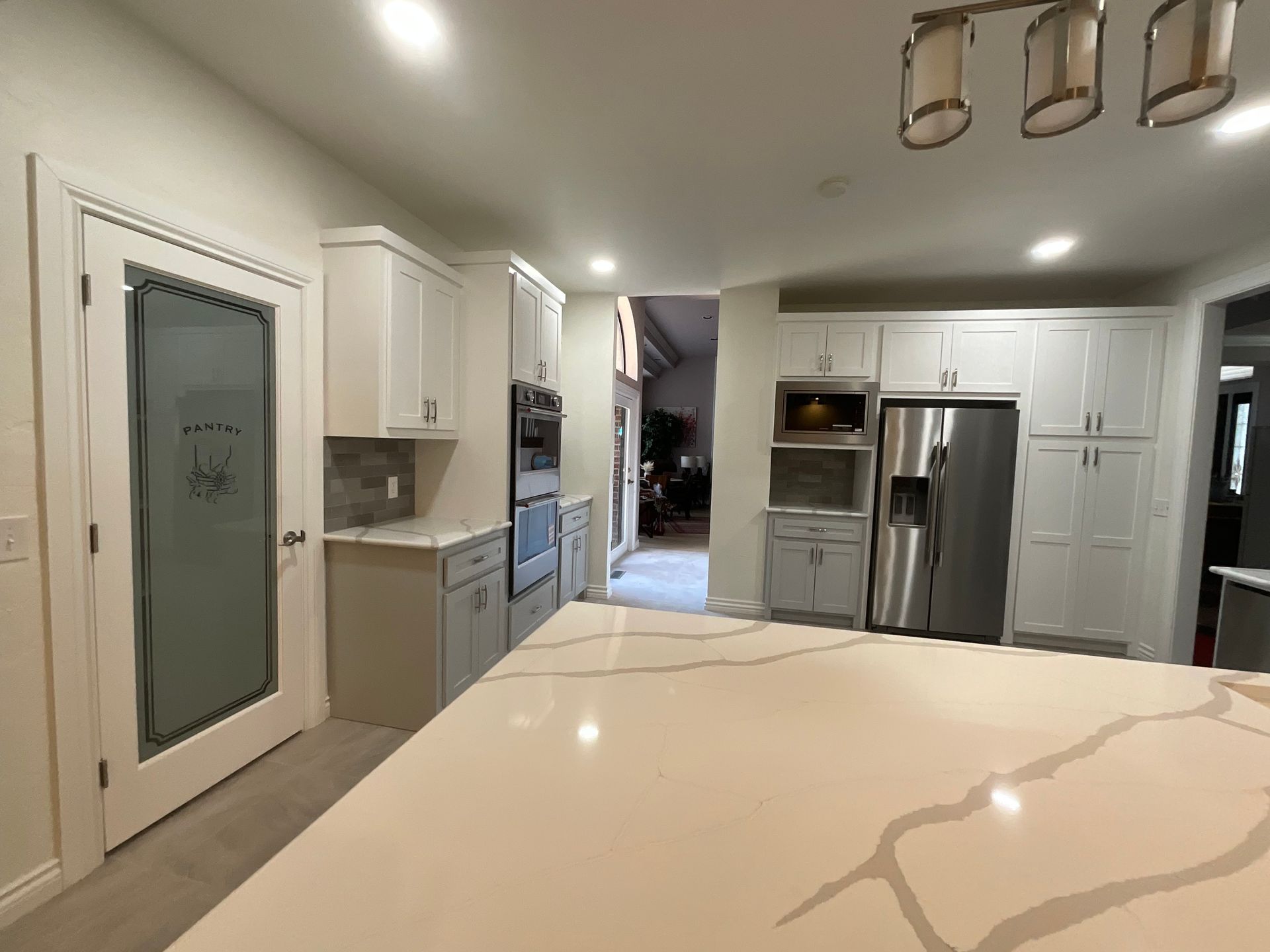 Bright kitchen with white cabinets, stainless steel appliances, and a marble island countertop