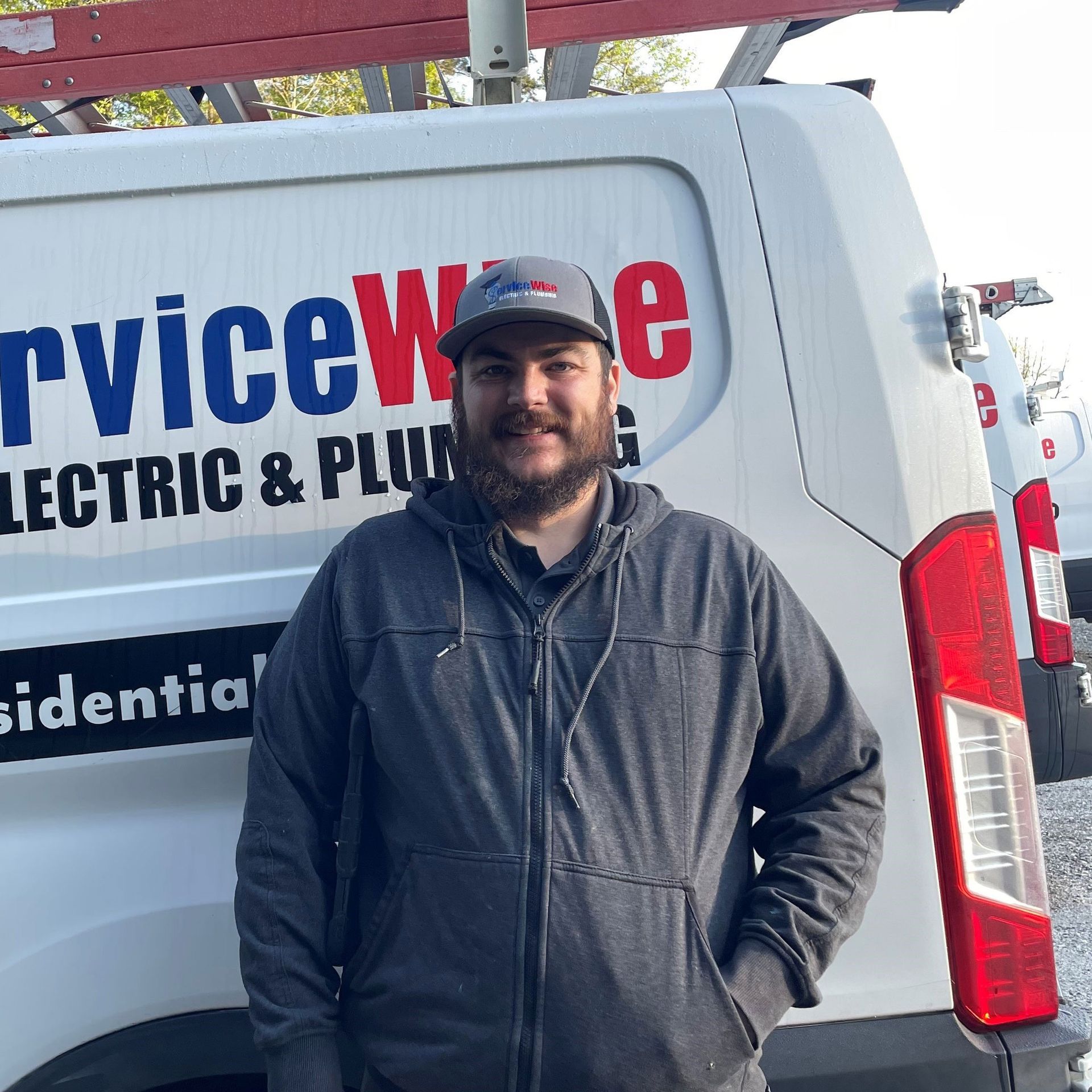 Man in gray jacket stands in front of a white van with