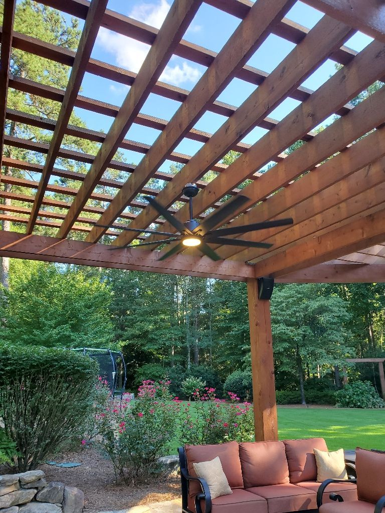 Pergola with ceiling fan over outdoor seating, overlooking a garden.