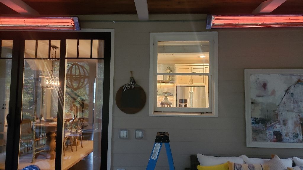 Outdoor patio with infrared heaters, door to interior dining, window to kitchen, and artwork.