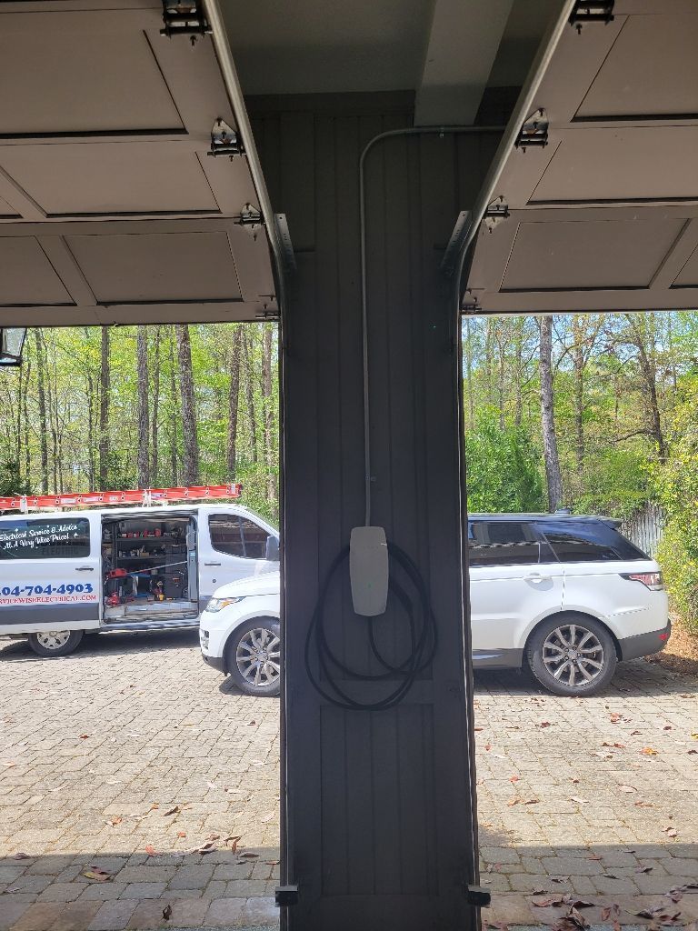 Electric vehicle charger mounted on a dark-colored column inside a garage, with a white SUV parked nearby.