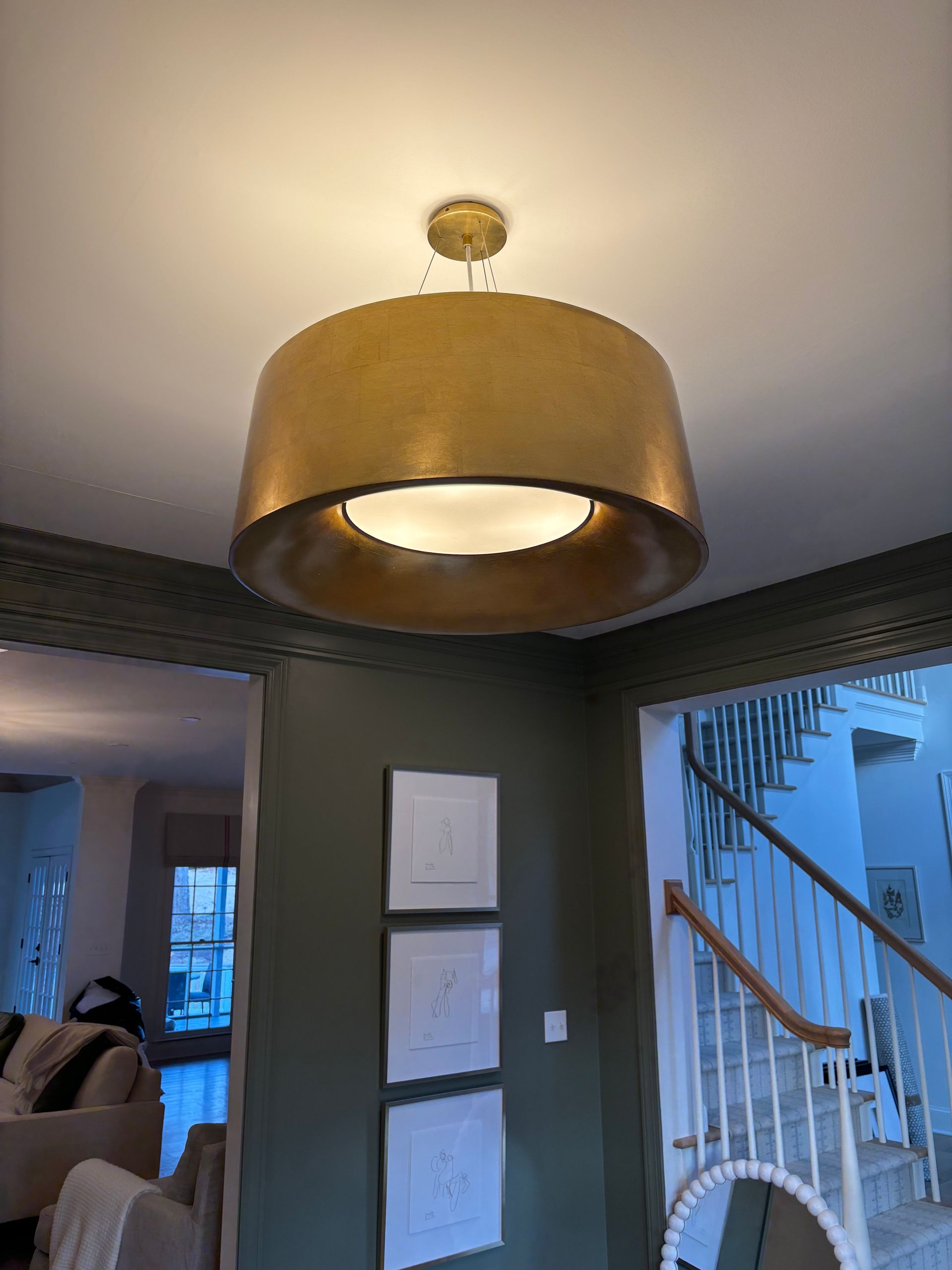 Gold pendant light fixture hanging from a white ceiling, illuminating a room.