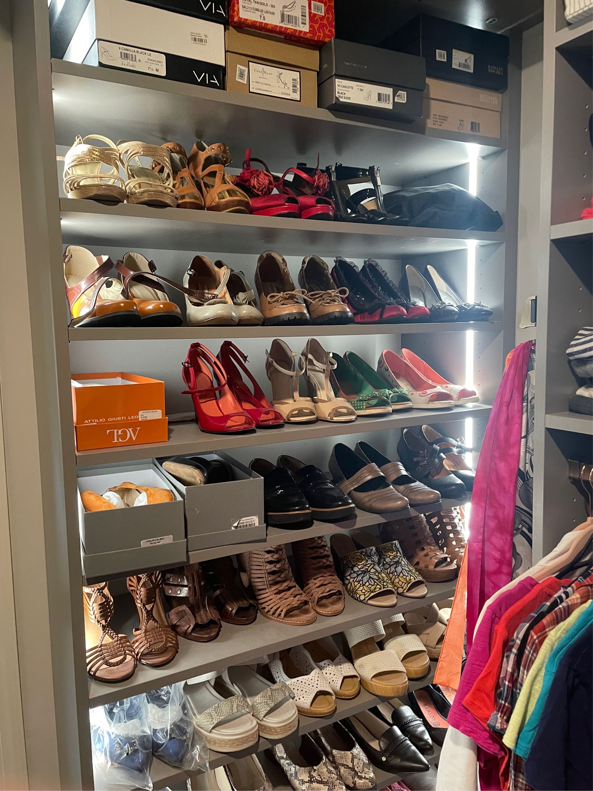 Shelves filled with various women's shoes and shoeboxes in a walk-in closet.