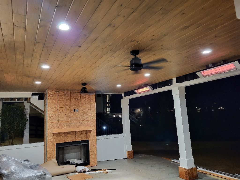 Covered outdoor patio with wood ceiling, recessed lights, fireplace, ceiling fan, and infrared heaters.