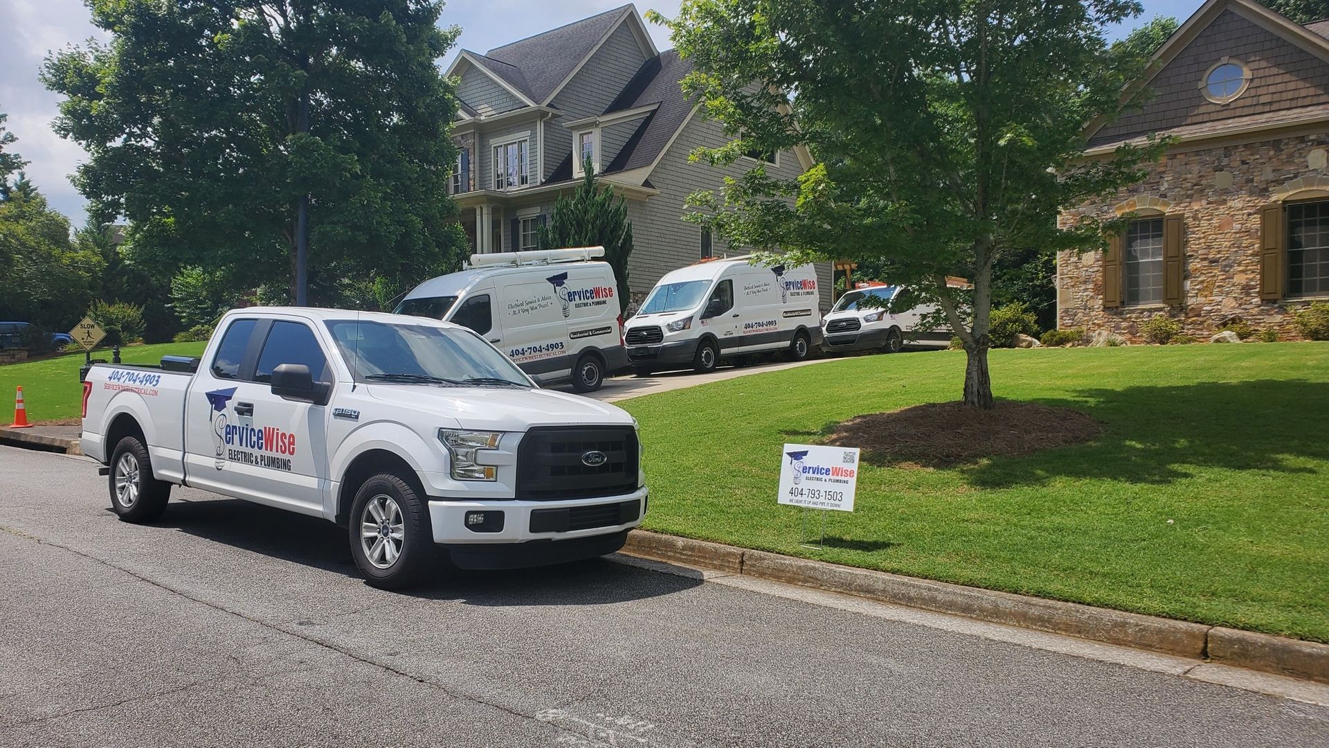White trucks and vans parked in front of large houses, potentially for a service.