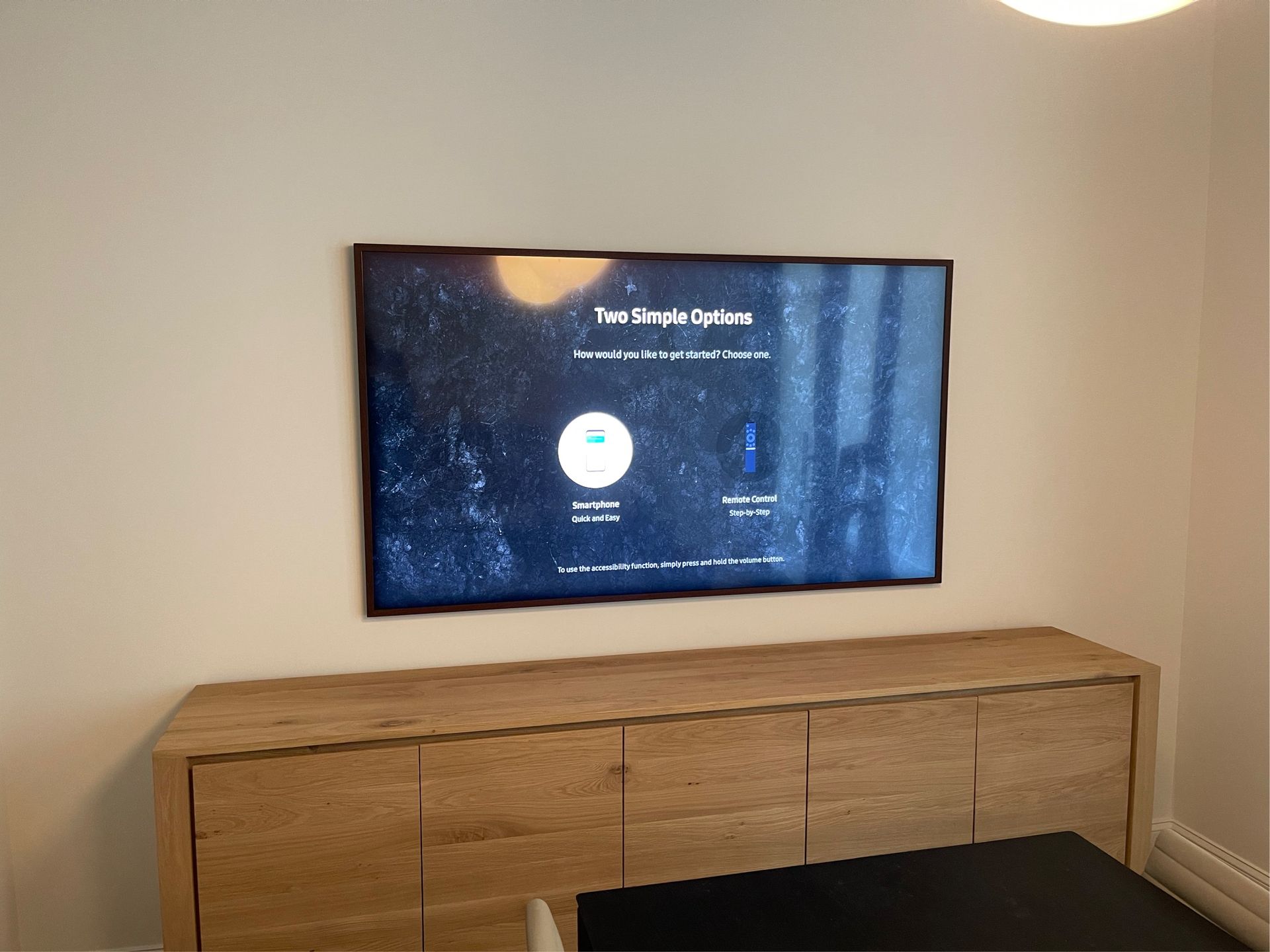 A wall-mounted TV displaying a screen with circular buttons, above a wooden cabinet.