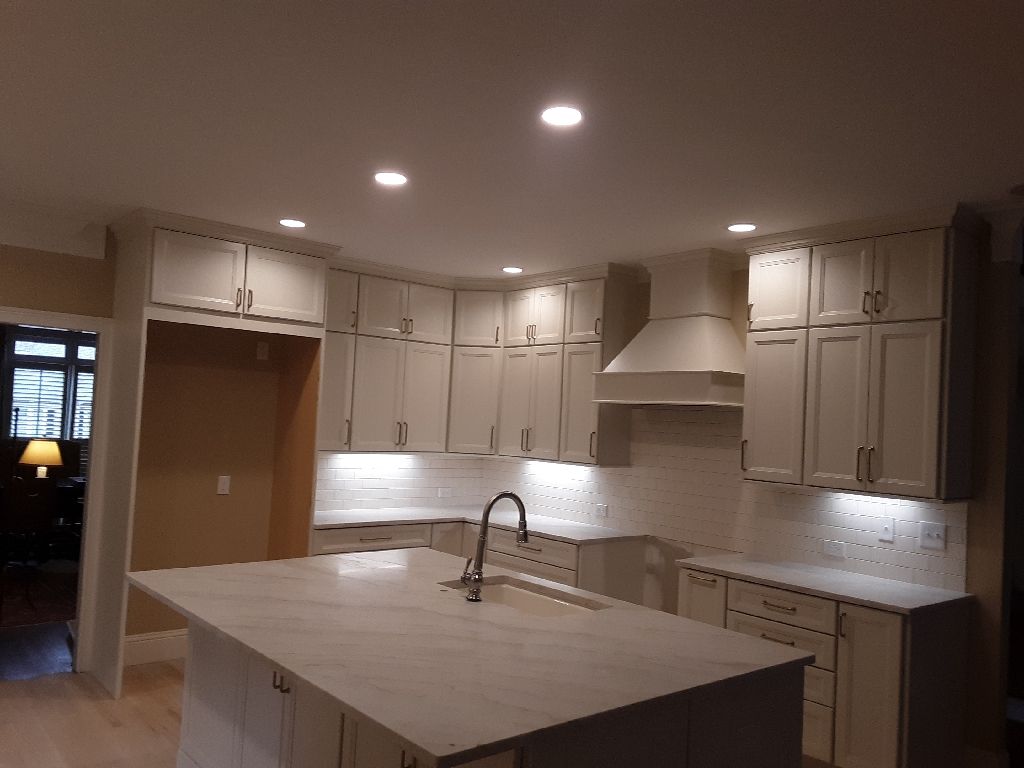 Modern kitchen with white cabinets, island, and tile backsplash.