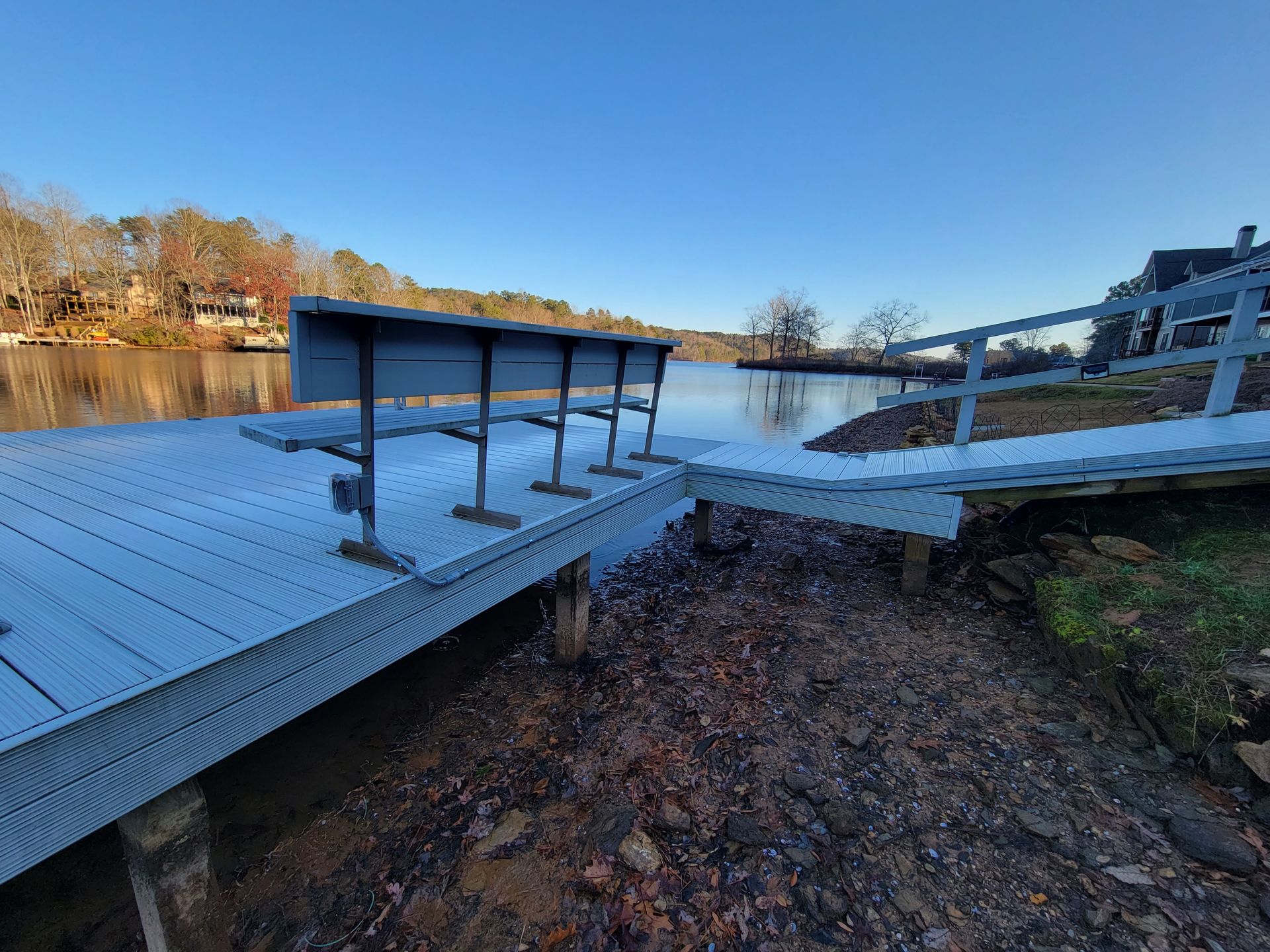 Wooden dock extending into a calm lake on a sunny day.