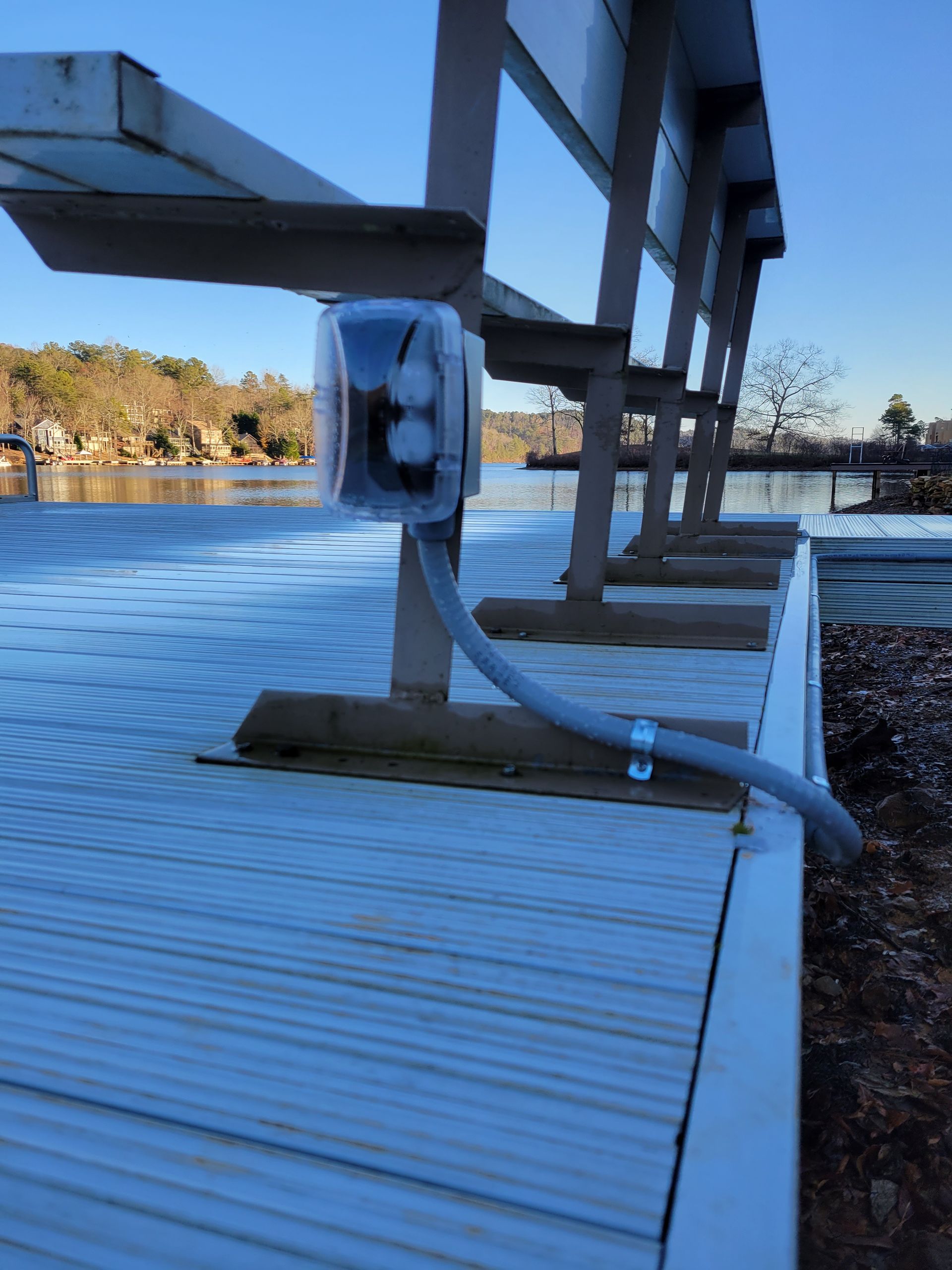 Electrical outlet box on a dock near water, next to a row of benches.