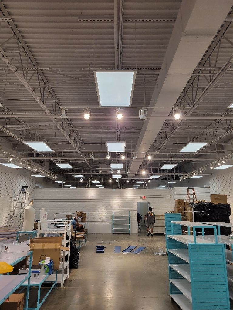 Interior of a large store with high ceilings, several skylights, and shelving. A person stands near a door.