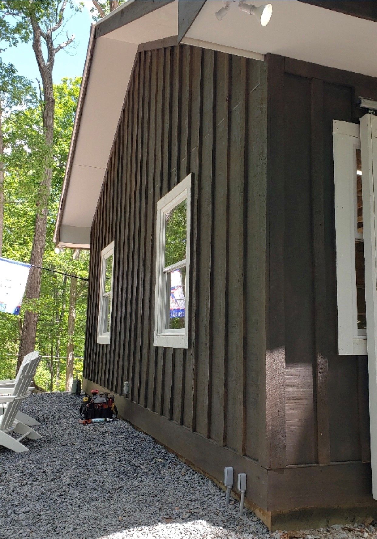 Dark brown cabin exterior with white-framed windows, white trim, and gravel ground.