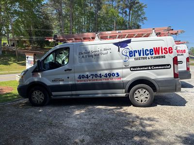 Two women, one on phone, one holding papers, both smiling, gray background.