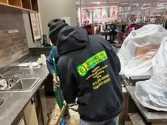 A man is cleaning a kitchen counter with a mop.