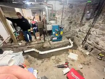 A man is standing in a basement next to a boiler.